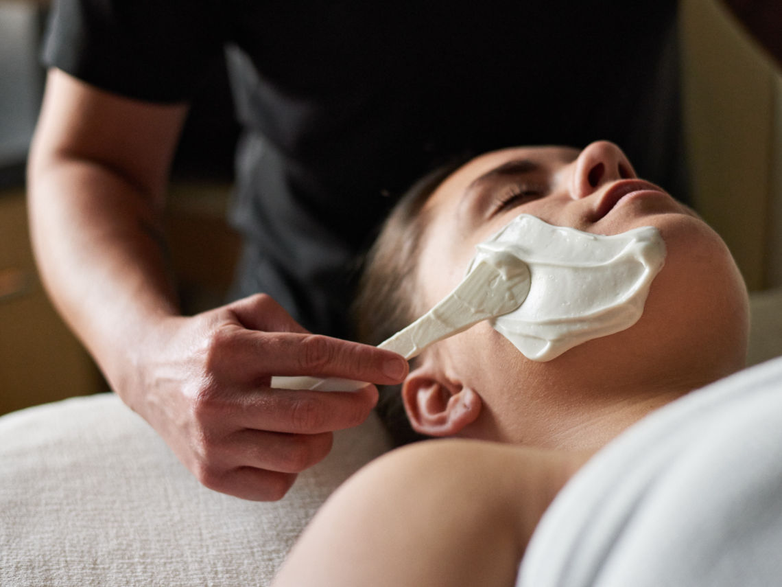 artisan applying face mask to guest