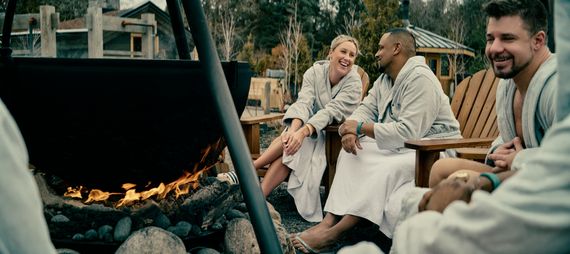 a couple sitting outside around a fire