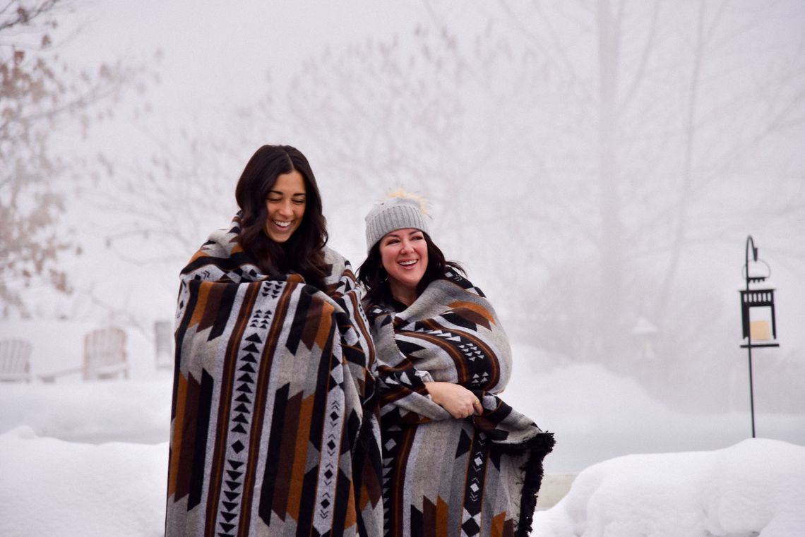 two women laughing in a wintery scenery with village blankets