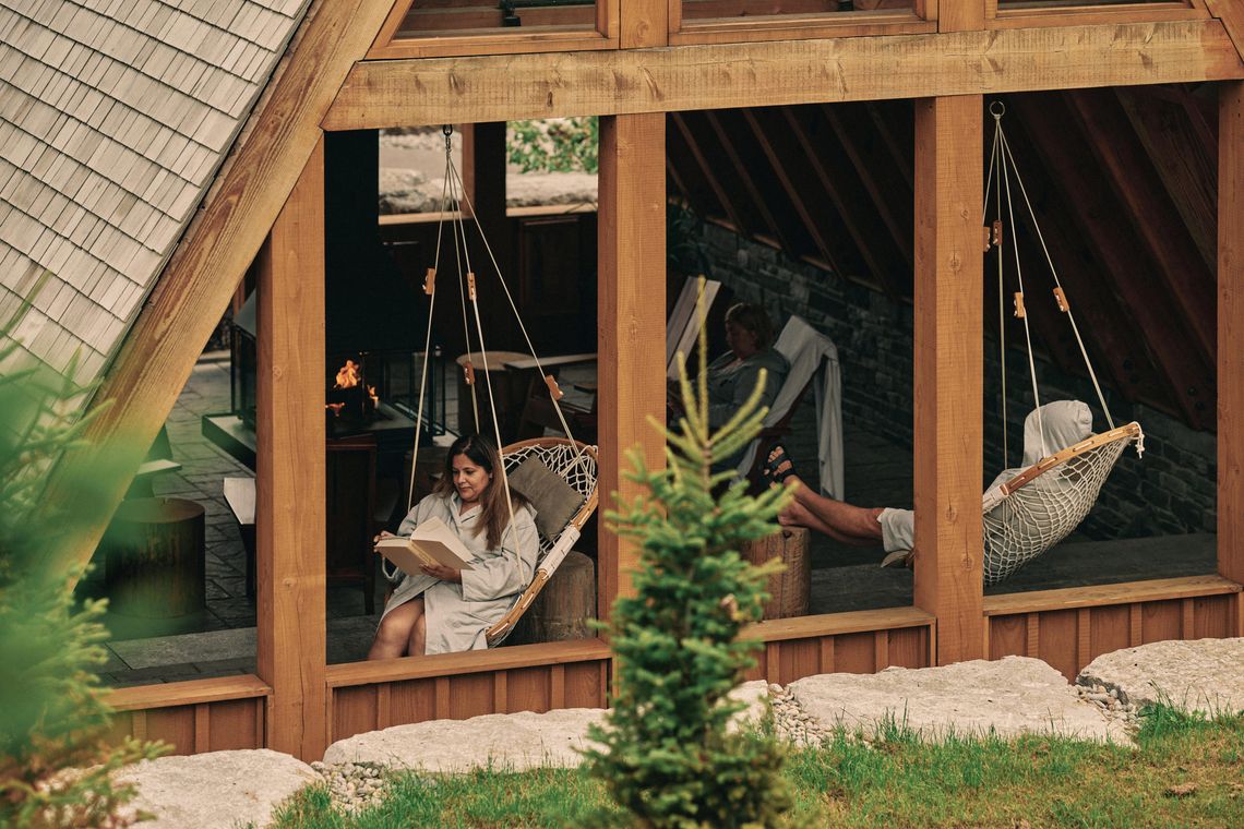 woman reading in a hammock chair in the a frame