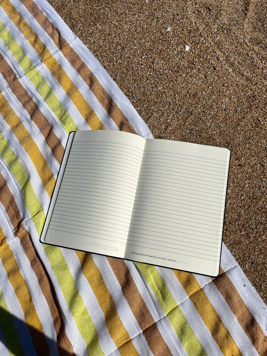 open note book on a sandy beach with towel