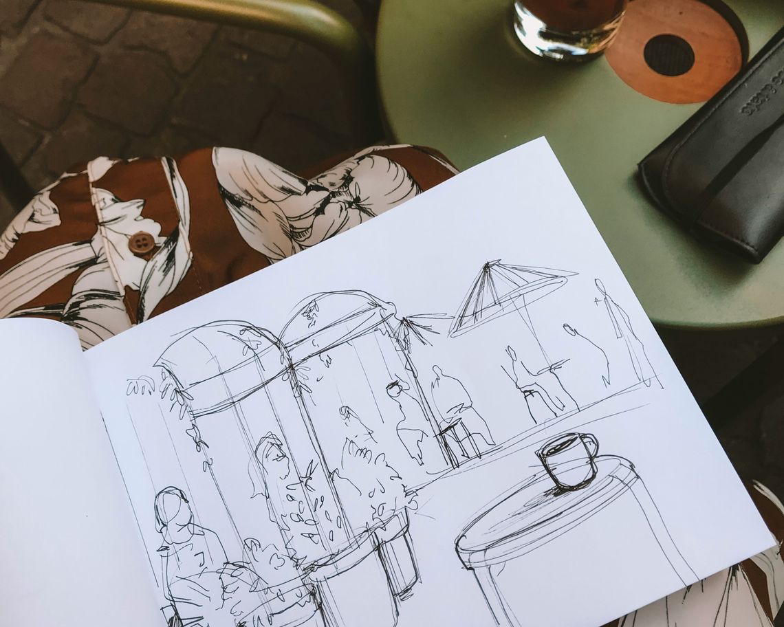 sketch of a coffeeshop in a sketchbook on a woman's knees