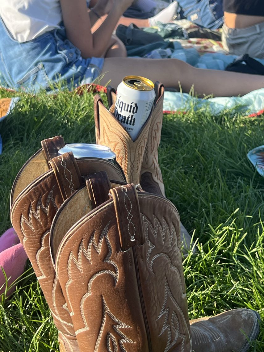 cowboy boots with a drink on a grassy field