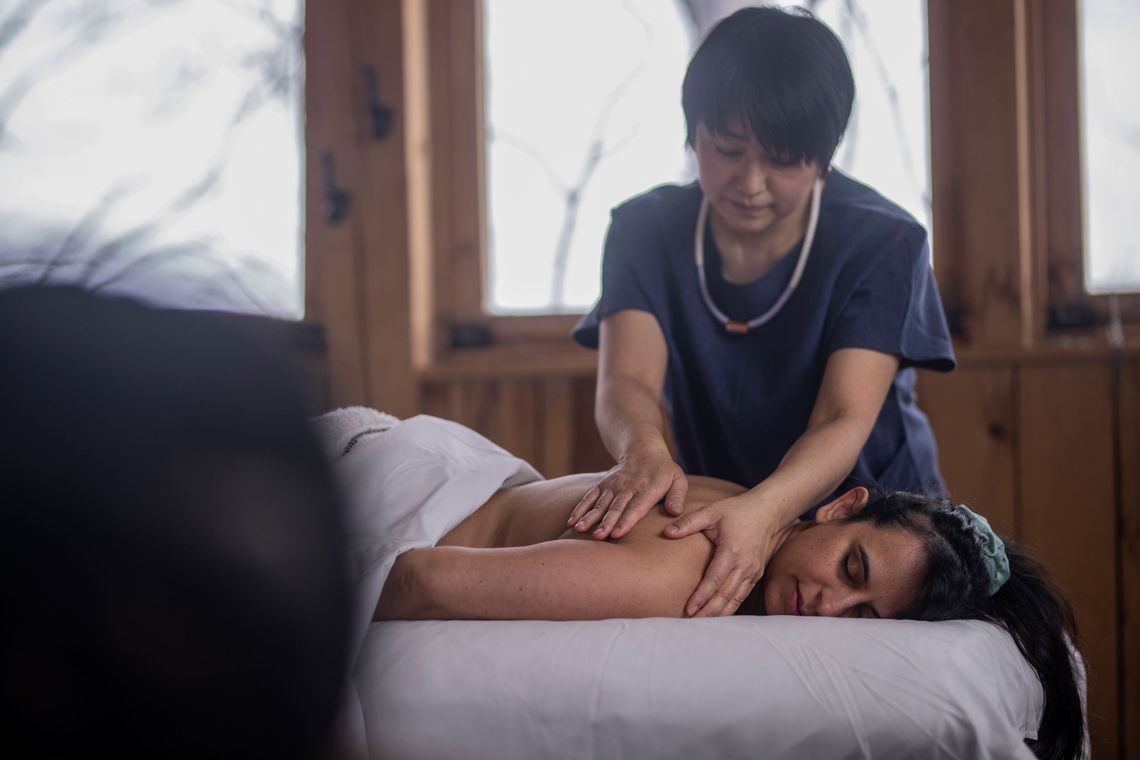 woman enjoying a massage in an outdoor cabin