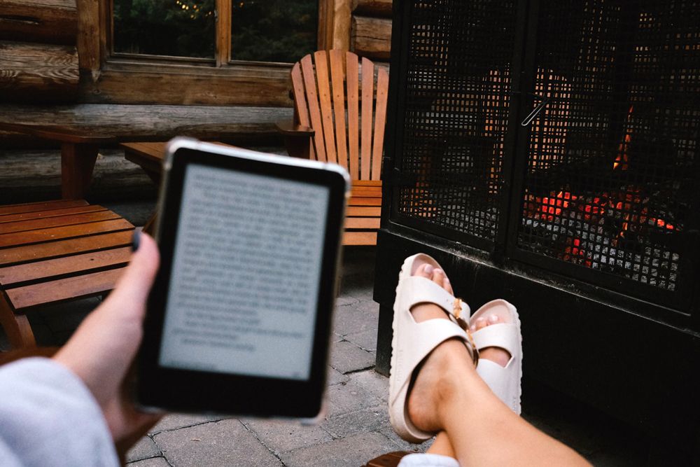 guest reading near an outdoor fireplace