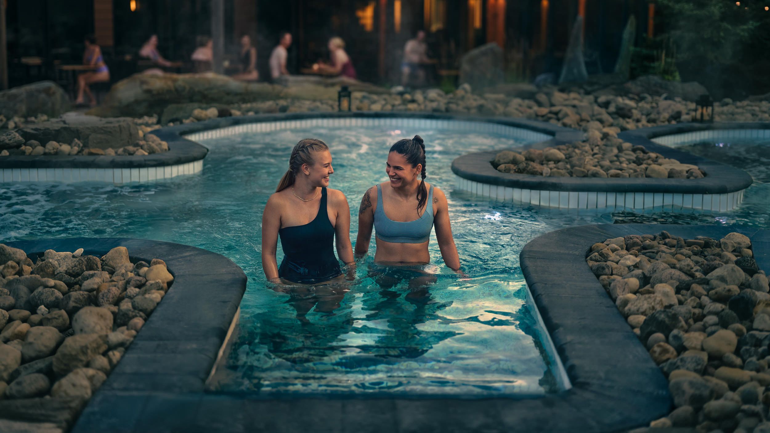 friends in a hot bath with view of lounge and patio in the background